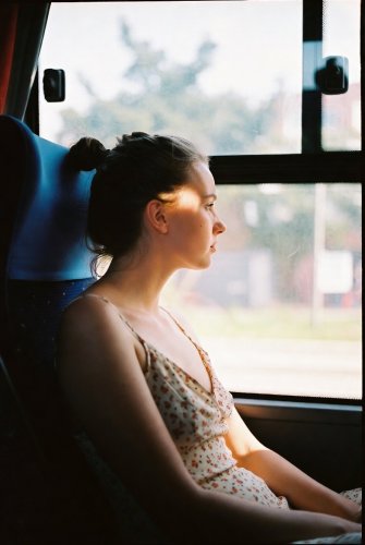 A brunette teen in a dress, braless, on a bus.