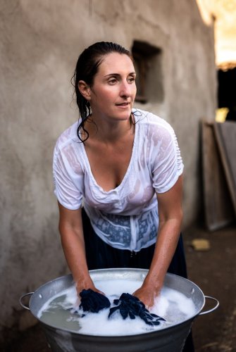 A middle-aged brunette woman wearing a wet, braless t-shirt.